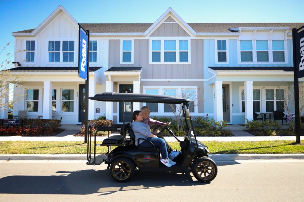 People in golf car passing through ryan homes